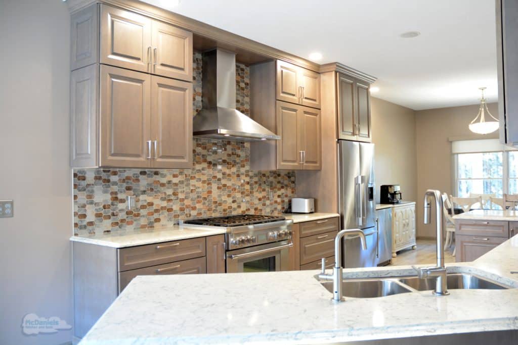 kitchen design with double sink, oven and chinmney hood, and large refrigerator