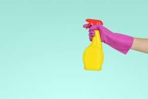 hand holding spray bottle of cleaner against a blue backdrop